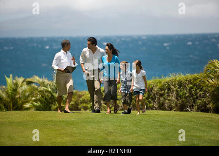 Familie im Gespräch mit Frau, beim Gehen über den Rasen. Stockfoto