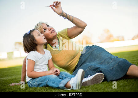 Großmutter und Enkelin sitzen auf dem Rasen Stockfoto