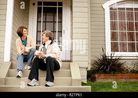 Eine Mutter und Tochter Nachholbedarf beim Kaffee auf der Vorderseite Stoop. Stockfoto