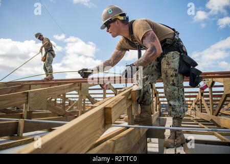 TINIAN, Commonwealth der Nördlichen Marianen (Nov. 14, 2018) Builder 3. Klasse William Mathis, von Ragland, Ala, und Builder 2. Klasse Anthony DeSalvo, von Savona, N.Y., sowohl zu Naval Mobile Konstruktion Bataillon 1, Loslösung Guam, messen Pfetten auf dem Dach der Volksschule während der Wiederherstellung Tinian Bemühungen zugeordnet. Service Mitglieder aus der gemeinsamen Region Marianas und US-Indo-Befehl sind die Verteidigungsministerium Unterstützung des Commonwealth von zivilen und lokalen Beamten der Nördlichen Marianen" als Teil der Federal Emergency Management Agency - unterstützt Super Ty Stockfoto