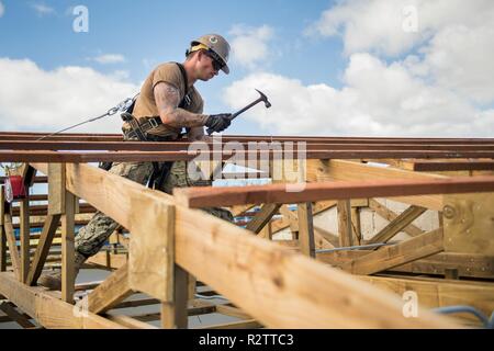 TINIAN, Commonwealth der Nördlichen Marianen (Nov. 14, 2018) Builder 3. Klasse William Mathis, zu Naval Mobile Konstruktion Bataillon 1, Loslösung Guam, von Ragland, Ala zugeordnet, Hammer einen Nagel in eine pfette auf dem Dach der Volksschule während der Wiederherstellung Tinian Bemühungen. Service Mitglieder aus der gemeinsamen Region Marianas und US-Indo-Befehl sind die Verteidigungsministerium Unterstützung des Commonwealth von zivilen und lokalen Beamten der Nördlichen Marianen" als Teil der Federal Emergency Management Agency - unterstützt Super Typhoon Yutu Wiederaufnahme Bemühungen. Stockfoto