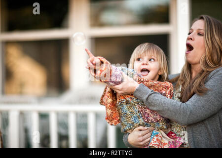 Mutter mit Kleinkind Tochter, wie Sie erreicht Bubble Pop. Stockfoto
