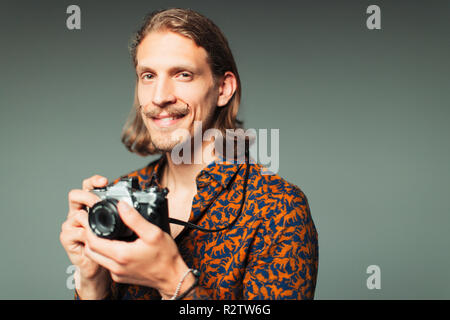 Portrait selbstbewussten jungen Mann mit Lenker Schnurrbart Holding retro Kamera Stockfoto