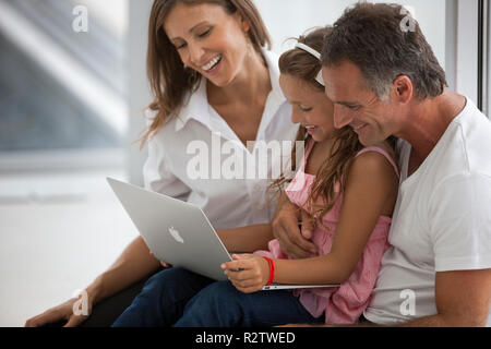 Middle-Aged Paare und ihre Tochter Lächeln, während sie sich an einer Lap Top. Stockfoto