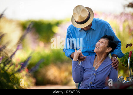 Lächelnde ältere Frau mit verstopfte Rohre umarmte von ihrem Ehemann. Stockfoto