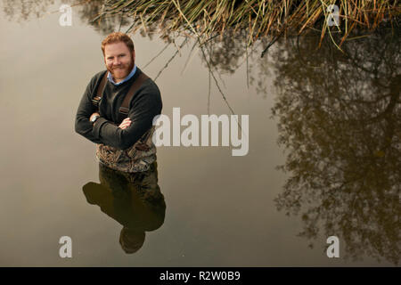 Porträt eines lächelnden Mitte erwachsener Mann, der Taille tief in einem See. Stockfoto