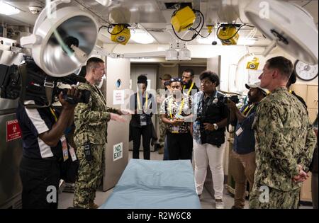 PORT Moresby, Papua Neu Guinea (Nov. 14, 2018) Lt.Cmdr. Andrew Sullivan erklärt medizinische Möglichkeiten an die lokalen Medien Mannschaft während einer Tour durch die amphibious Transport dock Schiff USS Green Bay LPD (20). Green Bay in Port Moresby die Vorbereitung mit Sicherheit Bemühungen im Vorfeld der Asia-Pacific Economic Cooperation (APEC) Konferenz zu unterstützen und ist die zweite US-Schiff nach Port Moresby in den letzten zwei Monate besuchen. Green Bay ist Teil der Amphibischen Squadron 11 und arbeitet in der Region Interoperabilität mit Partnern zu verbessern und dienen als ready-Response Force für jede Art von Kontingenz. Stockfoto