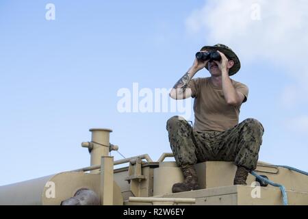Seaman Casey Tiraterra, Naval Beach Einheit 7 Larc Commander aus Sasebo Naval Base, Japan, sucht für kleine Wasserfahrzeuge während Strand be- und entladen von Fahrzeugen auf Saipan, Commonwealth der Nördlichen Marianen, November 12, 2018, als Teil der Super Typhoon Yutu Entlastung Bemühung. Mehr als 800 aktive Pflicht-, Reserve- und Guard service Mitglieder aus mehr als 20 verschiedenen Einheiten über alle Niederlassungen von Dienstleistungen innerhalb der USA Indopazifik Befehl unterstützen die Federal Emergency Management Lead recovery Anstrengungen, die Okt. 25 begann folgenden Super Typhoon Yutu. Stockfoto