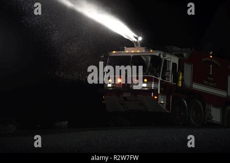 Ein feuerwehrauto Zum 92. Bauingenieur Squadron Feuerwehr zugeordnet schießt Wasser ein simuliertes Flugzeug Feuer bei Fairchild Air Force Base, Washington, November 8 2018 zu löschen. Fairchild Feuerwehr hat zahlreiche Fahrzeuge, die jeweils nur für eine bestimmte Sendung einstellen, einschließlich einem Flughafen Rettung Brandbekämpfung Fahrzeug, ein Motor, ein mobile Wasserversorgung Fahrzeug, Rettungswagen und State-of-the-art Gefahrgut Response Unit. Stockfoto