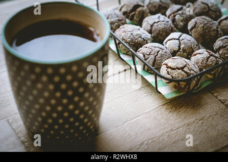 Schokolade crinkle Cookies in einem Korb mit einer Tasse Tee auf einem Holztisch. Nähe zu sehen. Querformat. Stockfoto