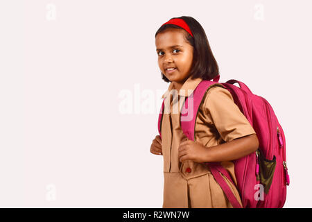 Kleine Mädchen in Schuluniform und Tasche vor der Kamera posieren. Pune, Maharashtra Stockfoto