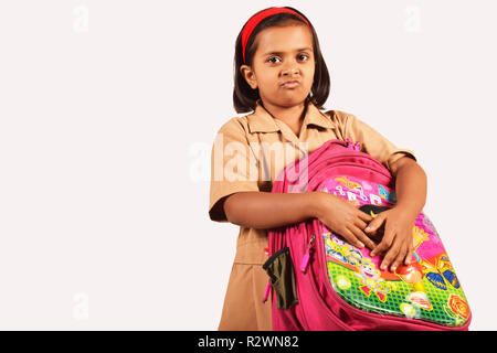 Kleine Mädchen in Schuluniform holding Schultasche und Suchen umgekippt. Pune, Maharashtra Stockfoto