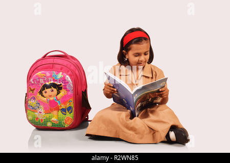 Kleine Mädchen in Schuluniform studieren mit Schultasche auf der Seite. Pune, Maharashtra Stockfoto