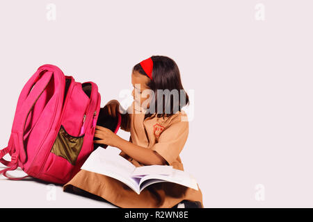 Kleine Mädchen in Schuluniform studieren mit Schultasche auf der Seite. Pune, Maharashtra Stockfoto