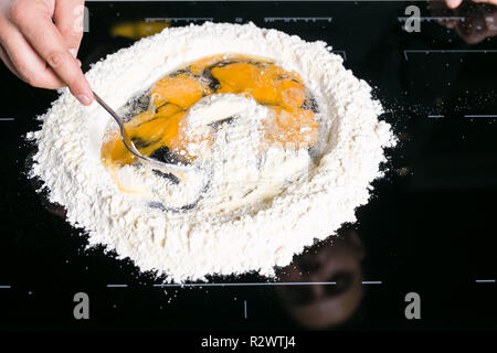 Koch prepairing frische Pasta Teig auf einer schwarzen Oberfläche Stockfoto