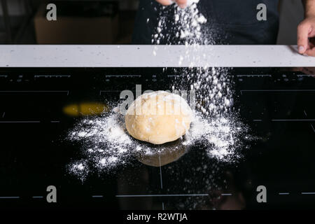 Koch prepairing frische Pasta Teig auf einer schwarzen Oberfläche Stockfoto