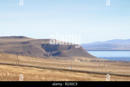 Herbst Landschaft mit blauen See und mit sanften Hügeln mit trockenen gelben Gras unter blauem Himmel in Chakassien, Russland abgedeckt Stockfoto
