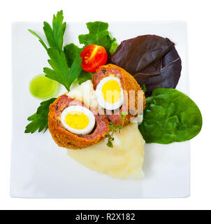 Blick von oben auf die halbierte Scotch Eier von wachteleier mit Garnierung, Kartoffelpüree, Gemüse und Grüns auf weiße Platte. Auf weissem Hintergrund Stockfoto