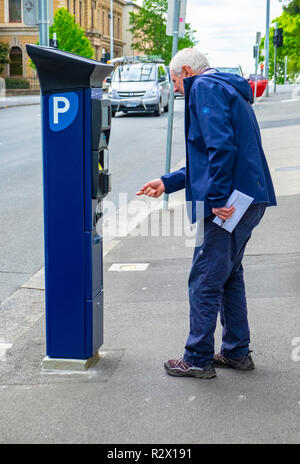 Ein älterer Mann, der versucht, herauszufinden, wie man auf einem neu installierten Solar Parkuhr in Hobart, Tasmanien betreiben Stockfoto