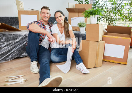 Junges Paar zwischen Umzugskisten beim Umzug in neue Wohnung oder Haus Stockfoto