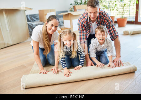 Familie und zwei Kindern in Ihrem Haus einen Teppich ausrollen Stockfoto