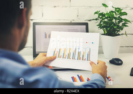 Mann bei der Arbeit mit Business Statistiken Daten in Office Stockfoto