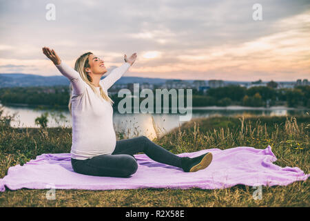 Schwangere Frau mit ausgestreckten Armen genießt die Zeit im Freien. Stockfoto