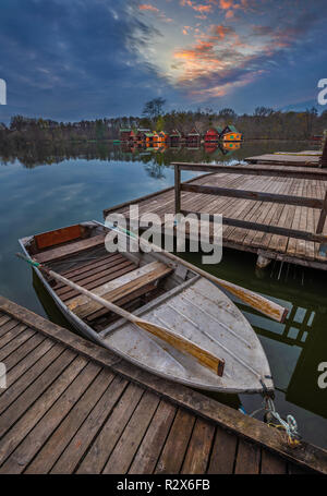 Tata, Ungarn - Fischerboot am See Derito (Derito) mit hölzernen Angeln Cottages und schönen Sonnenuntergang Stockfoto