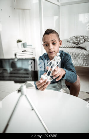 Angenehmer netter Junge mit einem Skelett Modell auf die Kamera Stockfoto