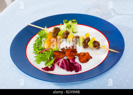 Gegrilltes Huhn Herz am Spieß mit Avocado mit gebratenen Pfifferlingen und Gemüse serviert. Stockfoto