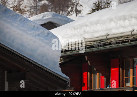 Viel Schnee in Schichten auf der Dachterrasse von Wohnhäusern an einem sonnigen Nachmittag Stockfoto