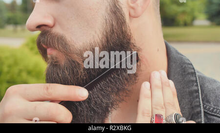 Die brutalen Mann Bürsten seinen Bart auf der Straße. Stockfoto
