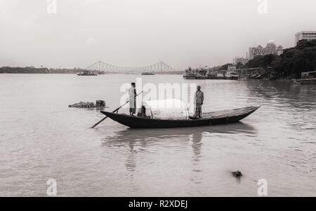Zwei Männer in traditionellen hölzernen Ruderboot überqueren Sie den Fluss Ganges (hooghly) auf einem ruhigen Morgen in Kalkutta, Indien. Stockfoto