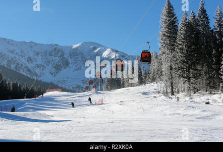 Jasna, Slowakei - Januar 25, 2017: Seilbahn Kabinen und Skifahrer an einem sonnigen Tag auf der Piste im Skigebiet Jasna Niedere Tatra, Slowakei. Stockfoto