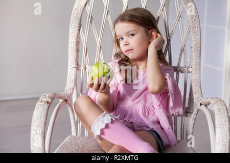 Ein kleines Mädchen sitzt auf einem Stuhl und trinken Milchshake Stockfoto