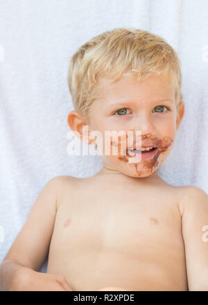 Portrait von blonden Jungen mit Schokolade auf seinem Gesicht auf weißem Hintergrund. Stockfoto