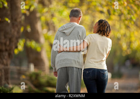 Weibliche Krankenschwester helfen, ein älterer Mann durch einen Park zu gehen. Stockfoto