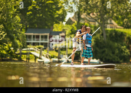 Vater und Sohn Spaß paddleboarding auf dem Fluss. Stockfoto
