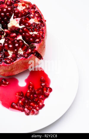 Reife saftige Granatapfel mit einem Tropfen und Samen Herzen bilden, Saft. Makro isoliert auf weißem Stockfoto