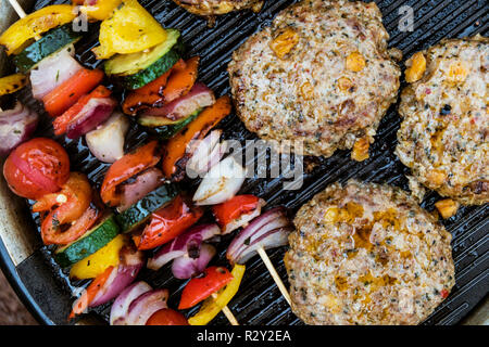 Essen auf einem Grill, Gemüse Kebabs und hausgemachten Burger, Kochen im Freien. Stockfoto