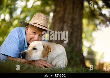 Ältere Menschen, die auf dem Gras mit seinem Hund. Stockfoto