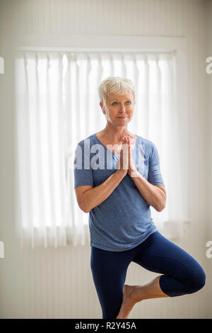 Reife Frau auf ein Bein während einer Yoga Praxis. Stockfoto