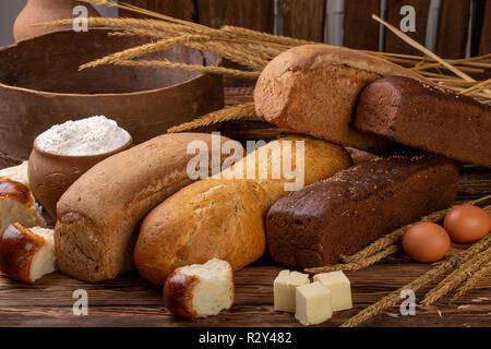 Anderes frisches Brot und ährchen von Weizen auf rustikalen Holzmöbeln Hintergrund. Kreative Gestaltung aus Brot. Gesunde Ernährung Konzept, flach Stockfoto