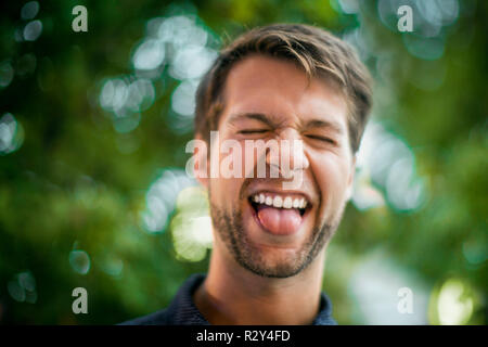 Glückliche junge Menschen ziehen ein Gesicht und seine Zunge heraus haften. Stockfoto