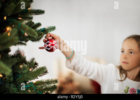 Junge Mädchen schmücken den Weihnachtsbaum. Stockfoto