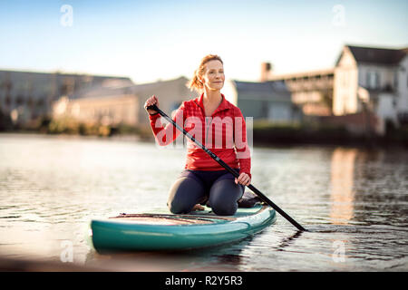 Mitte der erwachsenen Frau paddleboarding. Stockfoto