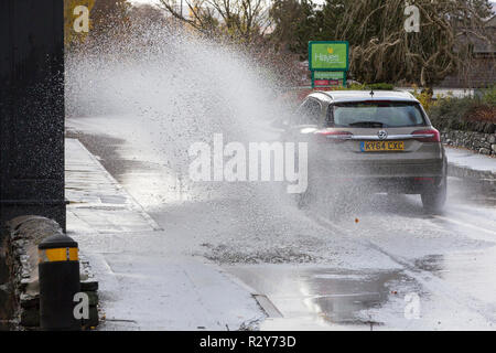 Autofahrer zu schnell gefahren durch grosse Pfützen einweichen Fußgänger und Unterkunft in Ambleside, Cumbria, Großbritannien. Stockfoto