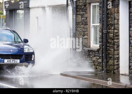 Autofahrer zu schnell gefahren durch grosse Pfützen einweichen Fußgänger und Unterkunft in Ambleside, Cumbria, Großbritannien. Stockfoto