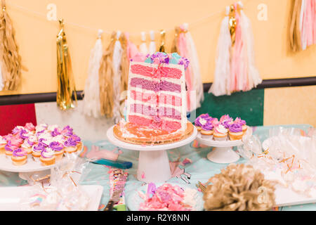 In Scheiben geschnitten groß Einhorn Kuchen mit rosa und lila Kuchen Schichten auf der kleinen Mädchen Geburtstag. Stockfoto