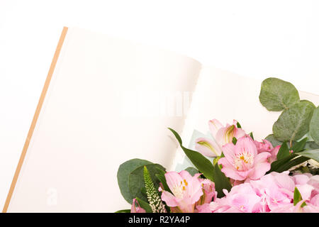 Öffnen Sie ein Notizbuch oder ein Tagebuch mit zartem Blumenschmuck auf dem weißen Tisch. Stockfoto